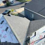Aerial view of roof during tear-off and dry-in, with new synthetic underlayment installed alongside remaining old shingles, Bend, Oregon