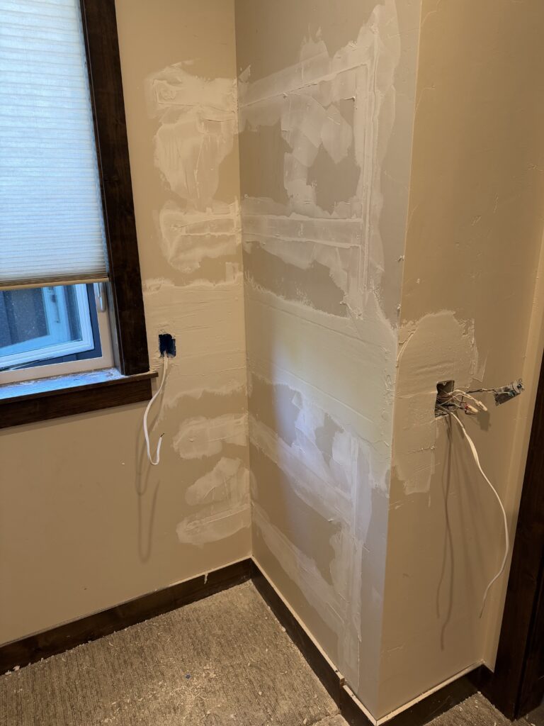 Drywall patching in progress near window, first coat applied, Sunriver, Oregon