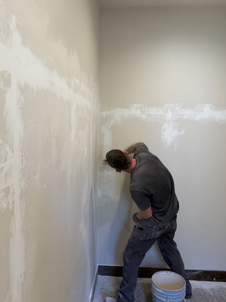 PNW crew member sanding a repaired drywall wall, Sunriver, Oregon