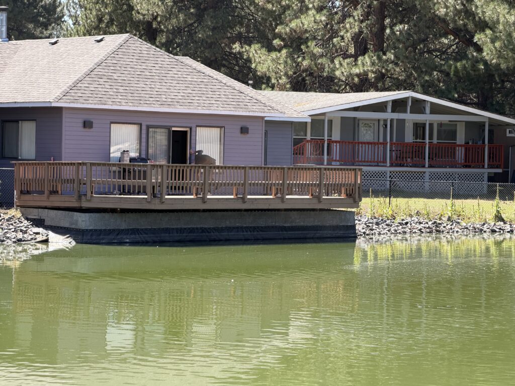 Wide view of the completed deck and new support wall from across the community pond