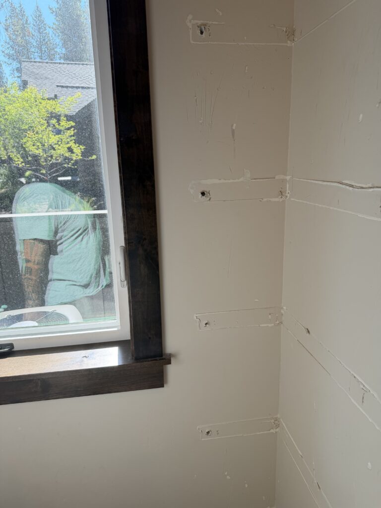 Bedroom wall near window with patched anchor holes before drywall repair, Sunriver, Oregon