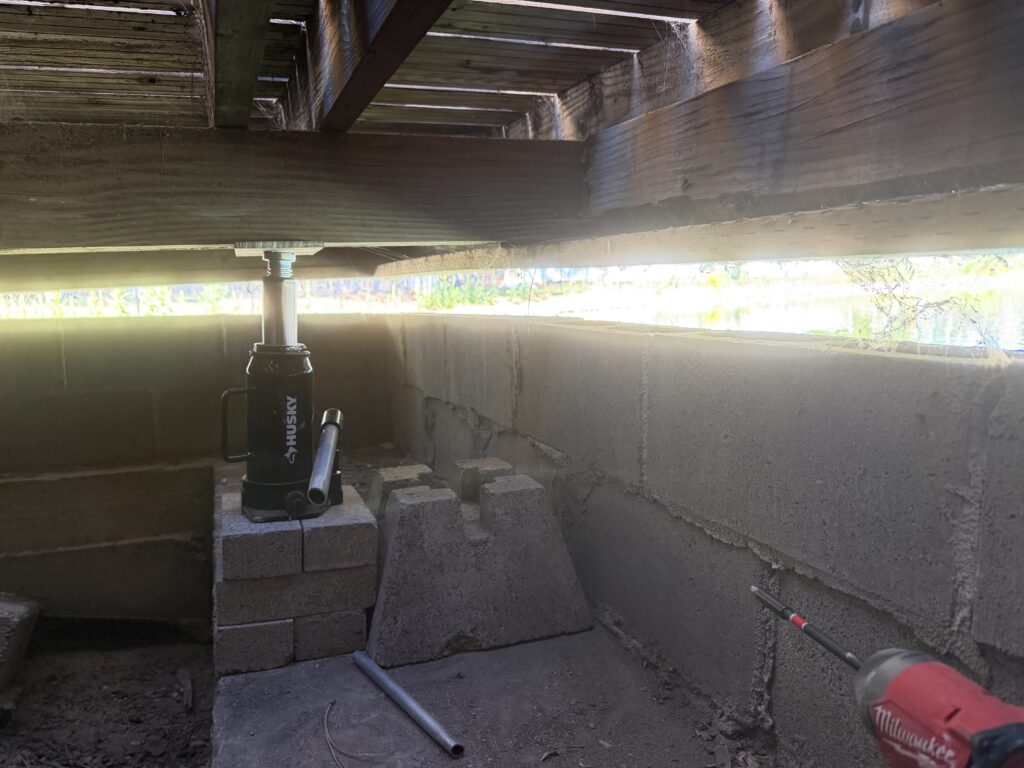Hydraulic jack supporting cinder block cribbing during deck leveling