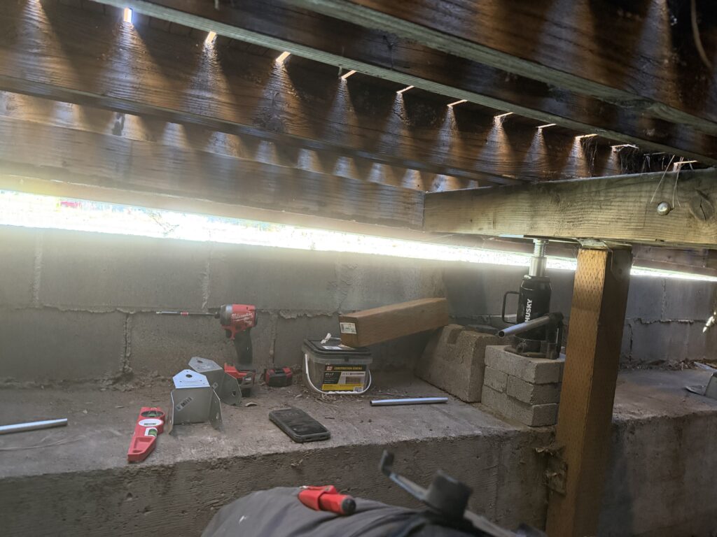 Tools including a jack, drill, and level staged during the leveling process
