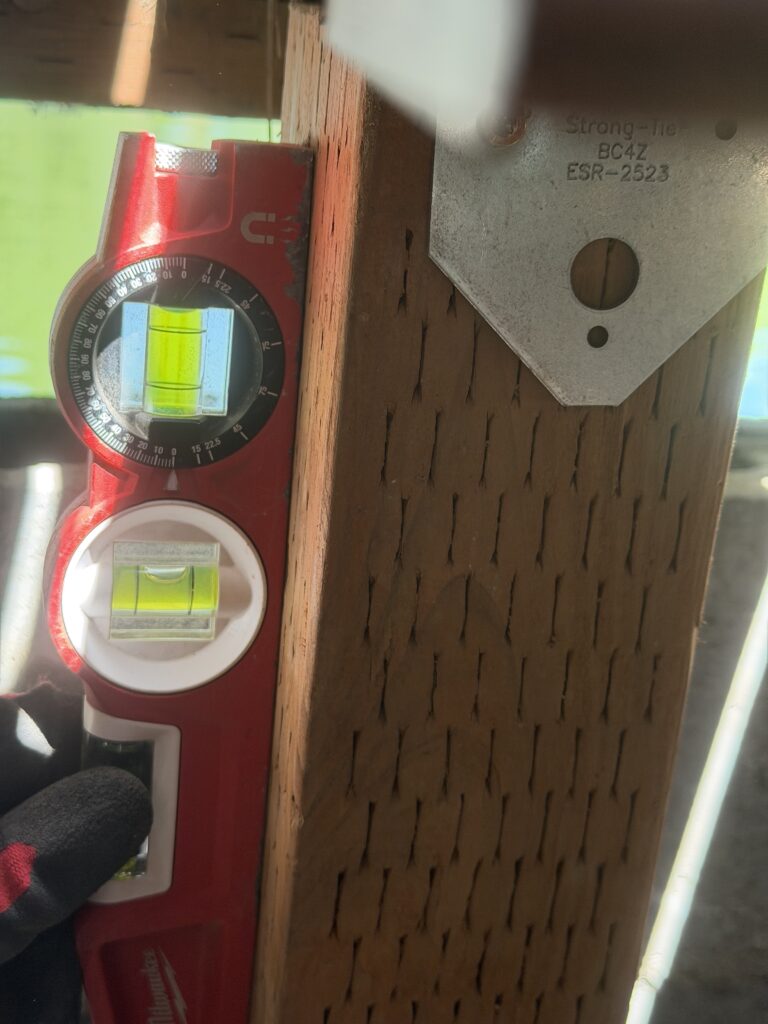 Torpedo level checking a support post for level during the leveling process