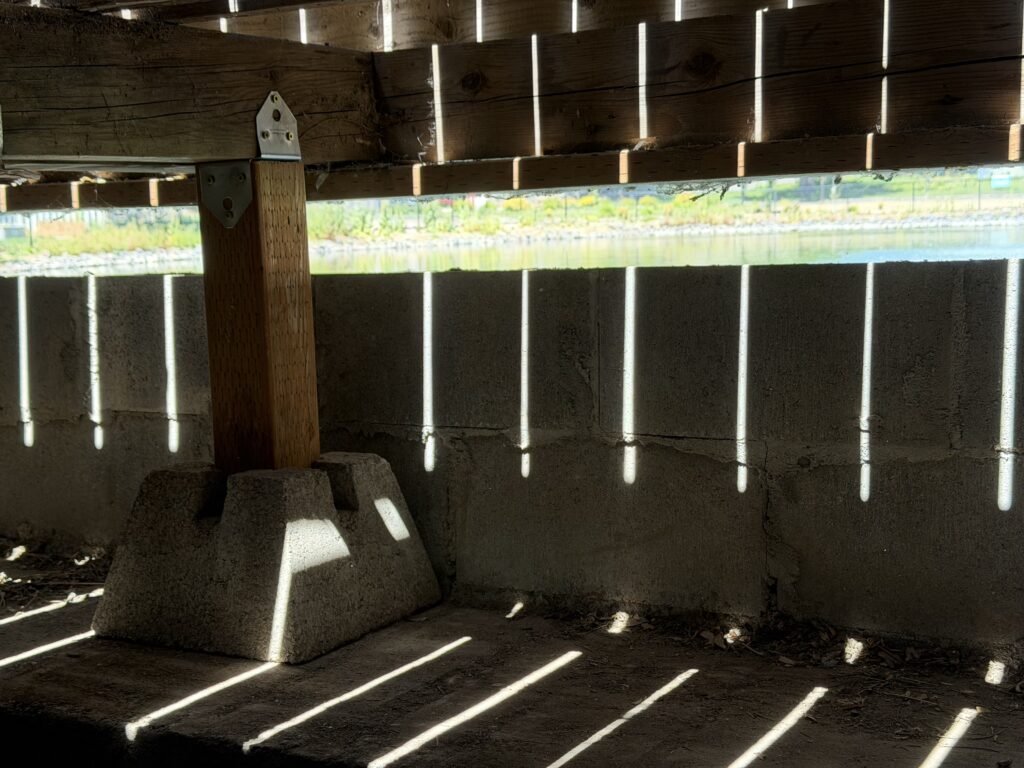 New support pier with a glimpse of the pond visible through the joist gap