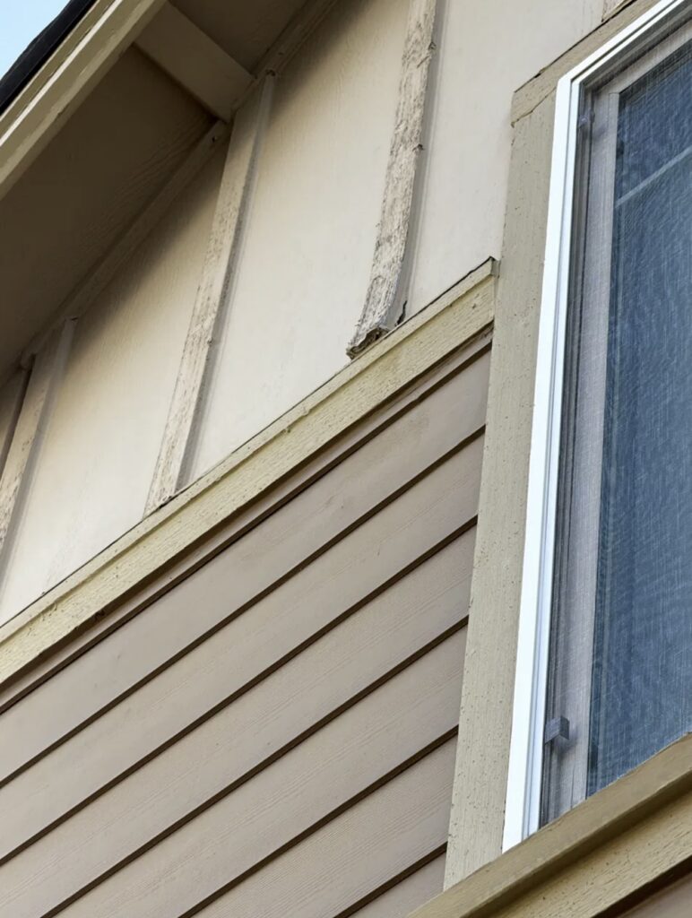 Low-angle view of a newly installed unpainted trim board during exterior repair work