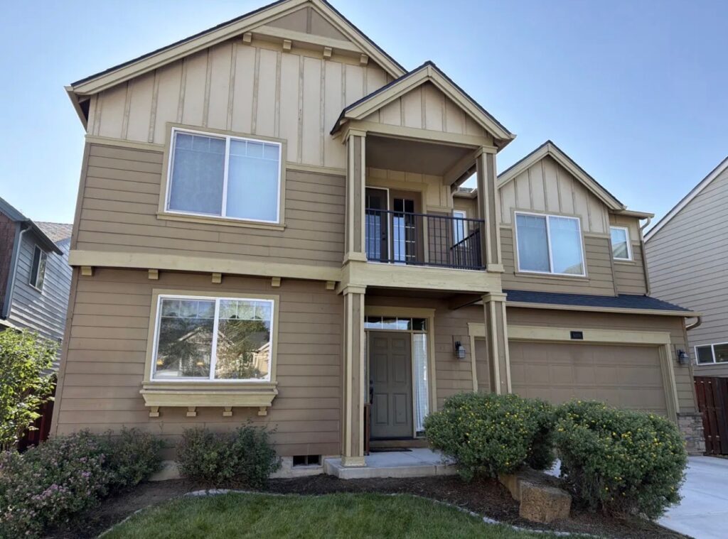 Two-story Bend, Oregon home before exterior painting, showing faded siding and trim in need of repaint